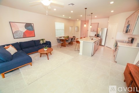 A living room with a blue couch and a dining area with a table and chairs.