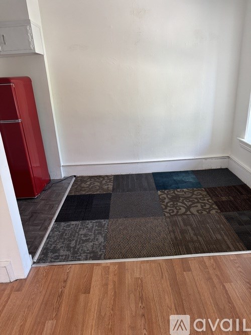A room with a red filing cabinet and a wooden floor with a rug.