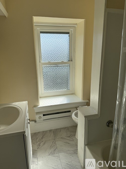 A bathroom with a window and a toilet.