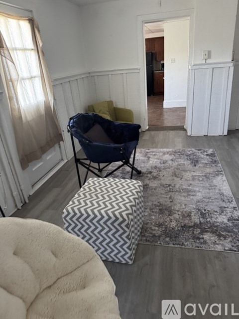A living room with a blue chair and a patterned ottoman.