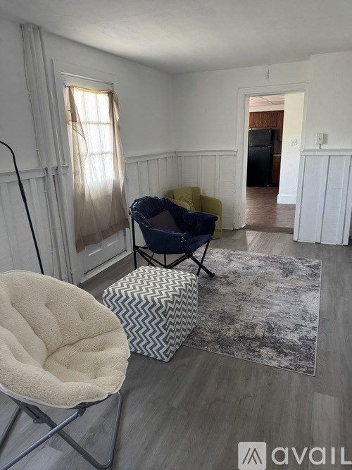 A living room with a white chair and a patterned ottoman.