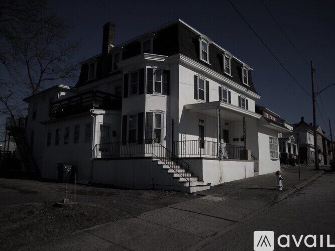 A large white house with a black roof and a balcony.