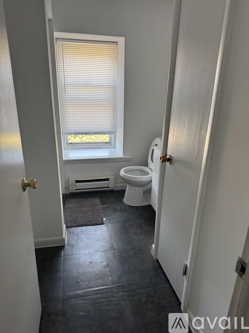 A bathroom with a toilet, window, and a door.