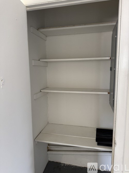 Empty white refrigerator with four shelves.