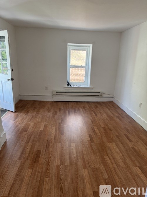 A room with wooden flooring and a window with blinds.