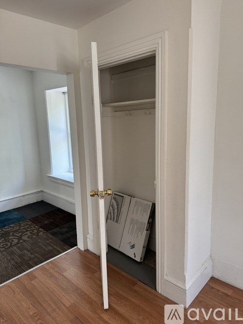 A white door with a gold handle is open to a small, empty closet.