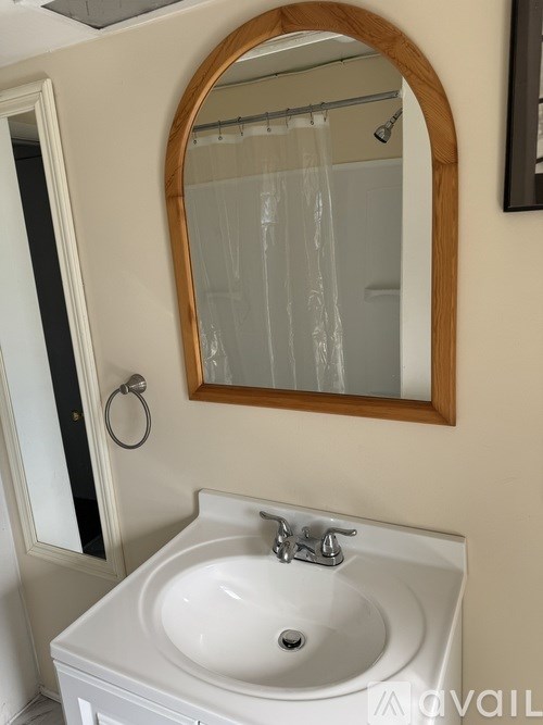 A white sink with a wooden framed mirror above it.