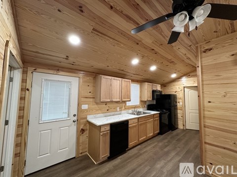 A kitchen area with wooden cabinets and a black refrigerator.