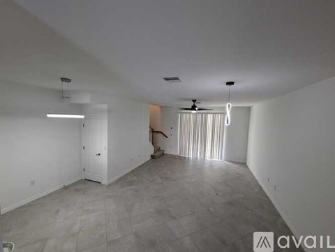A spacious room with a ceiling fan and a door leading to another room.