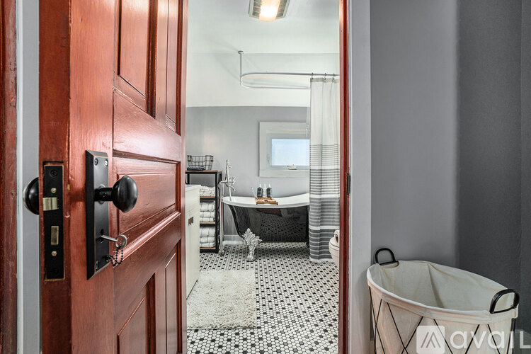 A bathroom with a black and white floor and a wooden door.