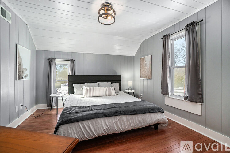 A bedroom with a large bed and a window with curtains.