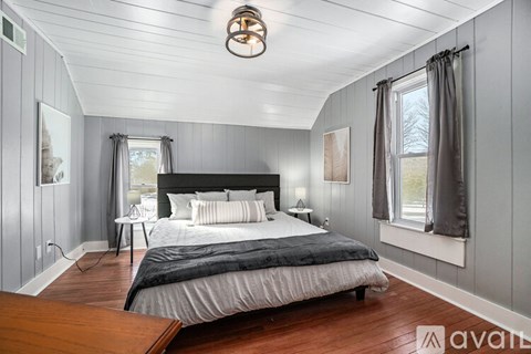 A bedroom with a large bed and a window with curtains.