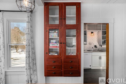 A kitchen with a wooden cabinet and a window with curtains.