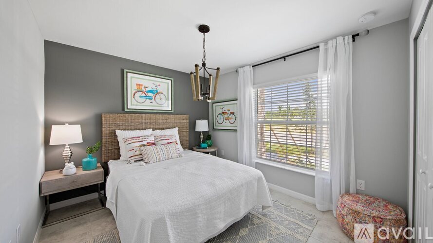 A bedroom with a large bed, a nightstand with a lamp, and a window with curtains.