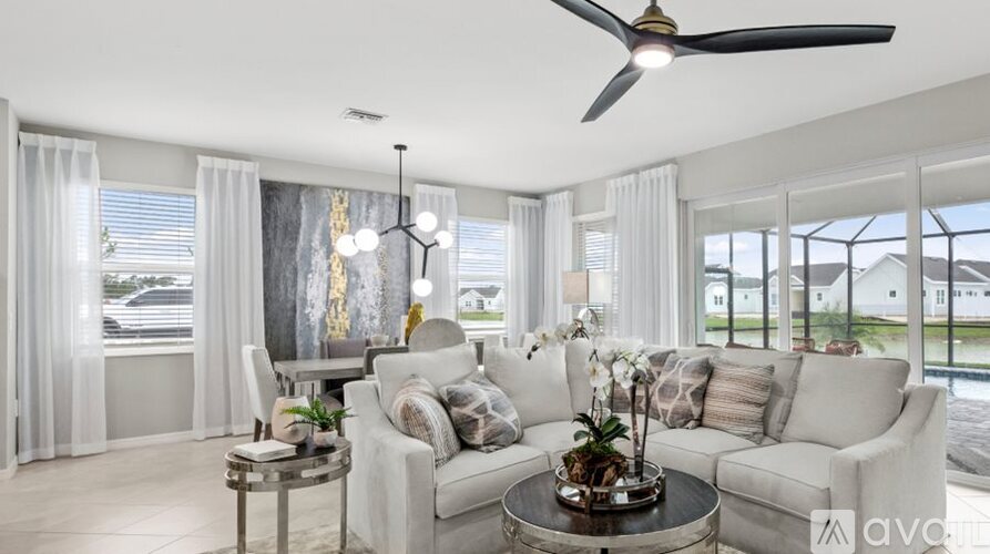 A living room with a white sofa, a round coffee table, and a ceiling fan.