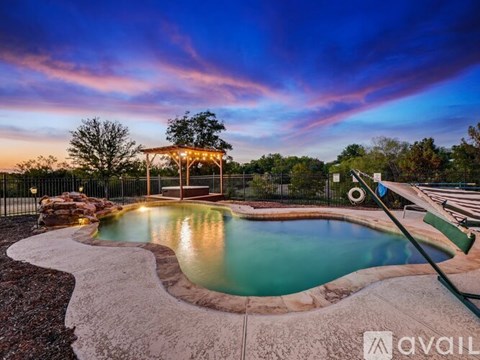 A pool with a hot tub and a gazebo in the background.