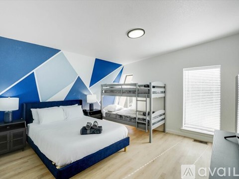 A bedroom with a large bed and bunk beds in the background.