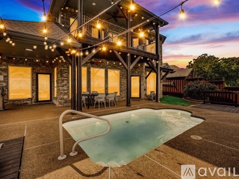 A pool in a backyard with lights strung above it.