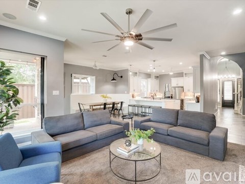 A living room with a grey sofa and a ceiling fan.
