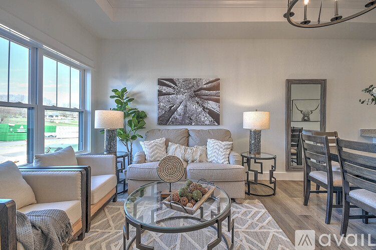 A living room with a glass coffee table and a grey sofa.