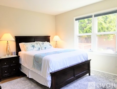A bedroom with a large bed and two lamps.