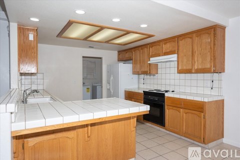 A kitchen with wooden cabinets and a white tiled backsplash.