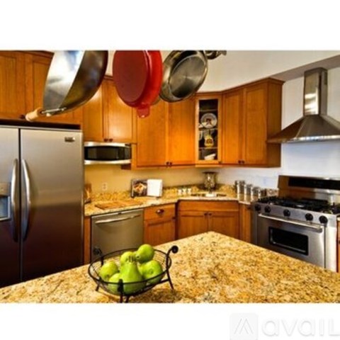 A kitchen with a granite countertop and a bowl of green apples on it.