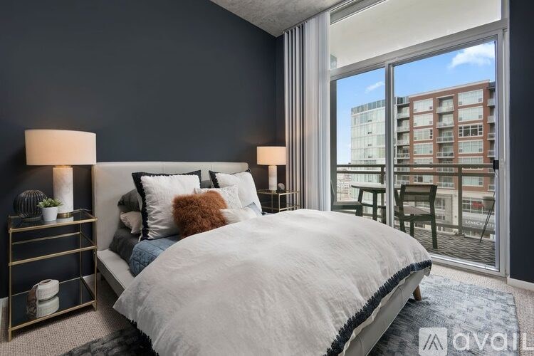 A bedroom with a large bed and a view of a cityscape through the window.