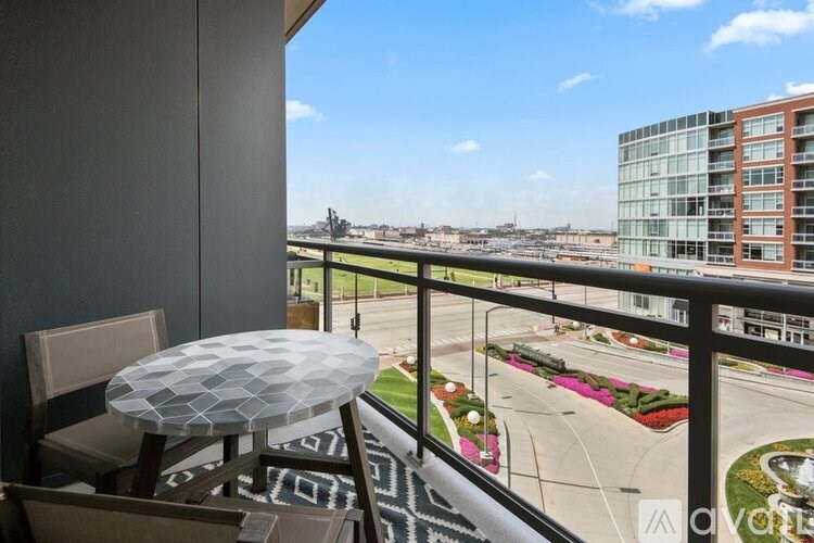 A balcony with a table and chairs overlooks a city street.