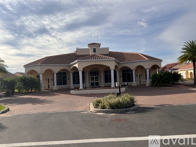 A large building with a red tiled roof and a driveway in front.