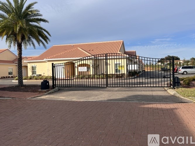 A house with a black gate and a palm tree in front.