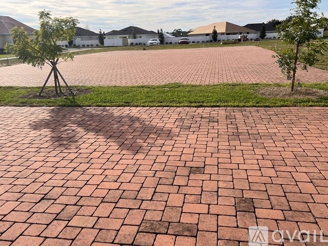 A red brick walkway leads to a white building.
