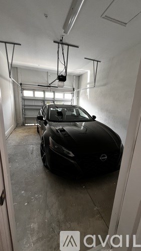 A black car is parked in a garage with a sign that says "available".