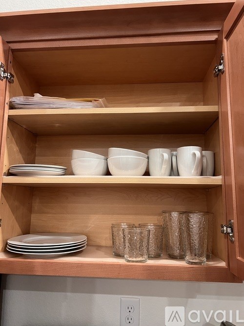 A wooden cabinet with plates and glasses on the shelves.