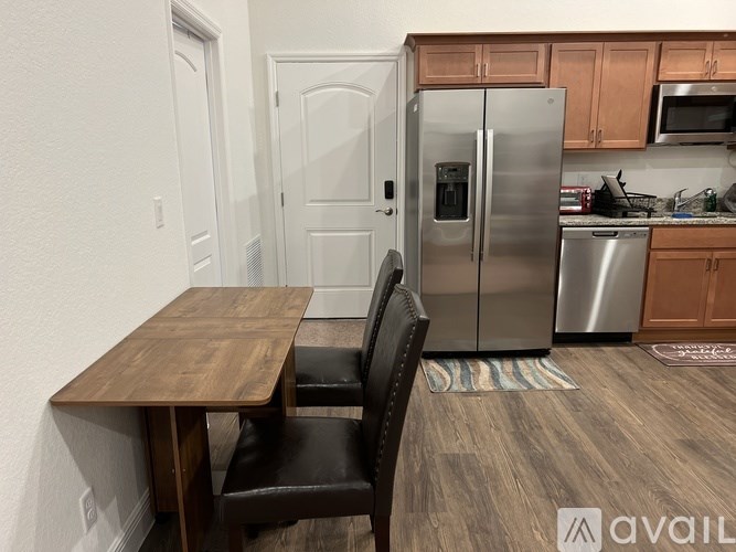 A kitchen with a table and chairs in the foreground and a refrigerator, microwave, and oven in the background.