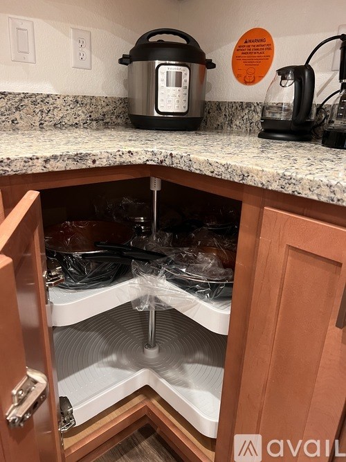 A black rice cooker is on a kitchen counter next to a coffee maker.
