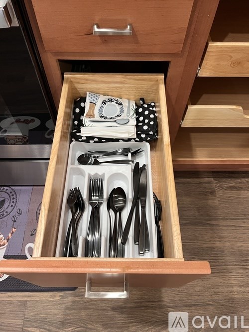 A drawer with utensils and a black and white polka dot cloth.