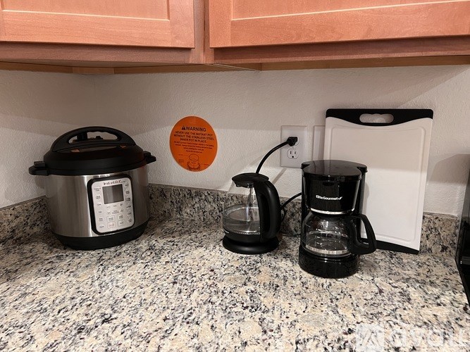 A black coffee maker and a black kettle on a granite countertop.
