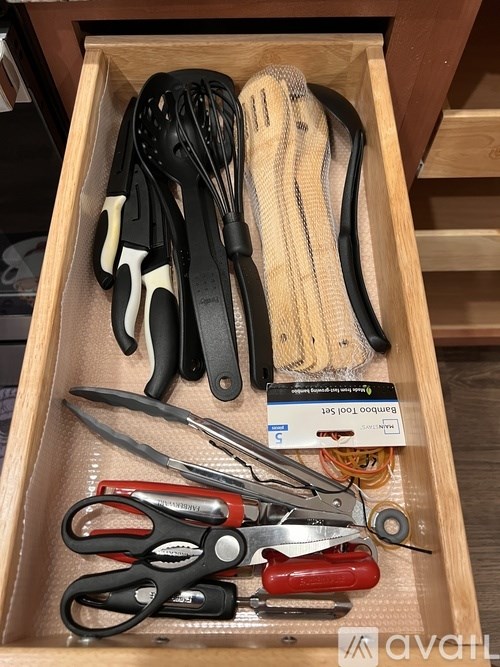 A drawer with kitchen utensils including scissors, a spatula, and tongs.