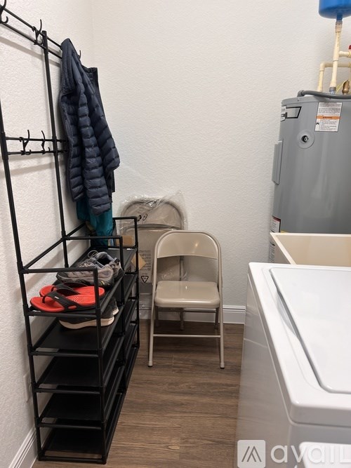 A small bathroom with a chair, a sink, and a rack with clothes hanging on it.