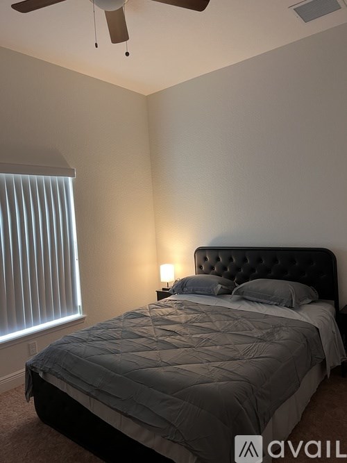 A bedroom with a bed, a ceiling fan, and a window with blinds.