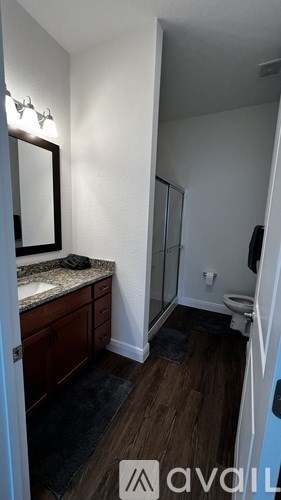 A bathroom with a toilet, sink, and mirror.