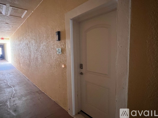 A hallway with a white door and a wall-mounted speaker.