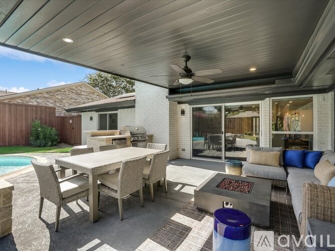 A patio with a table and chairs is covered by a roof.