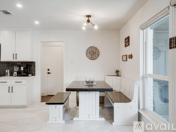 A kitchen with white cabinets and a black island.