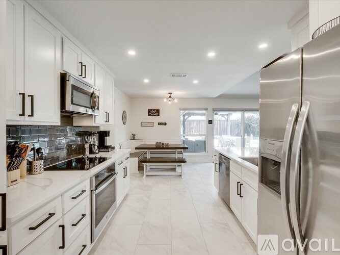 A modern kitchen with white cabinets and stainless steel appliances.