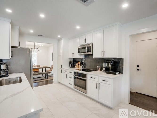 A modern kitchen with white cabinets and stainless steel appliances.