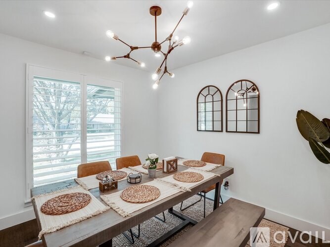 A dining room with a table set for four and a window letting in light.