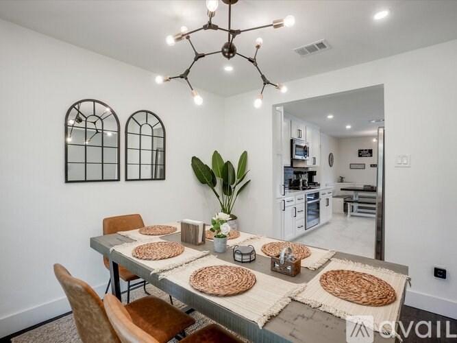 A dining room with a table set for six and a plant in the corner.