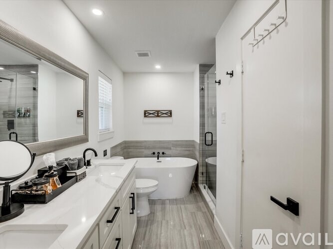 A modern bathroom with a large mirror, a white sink, and a white bathtub.